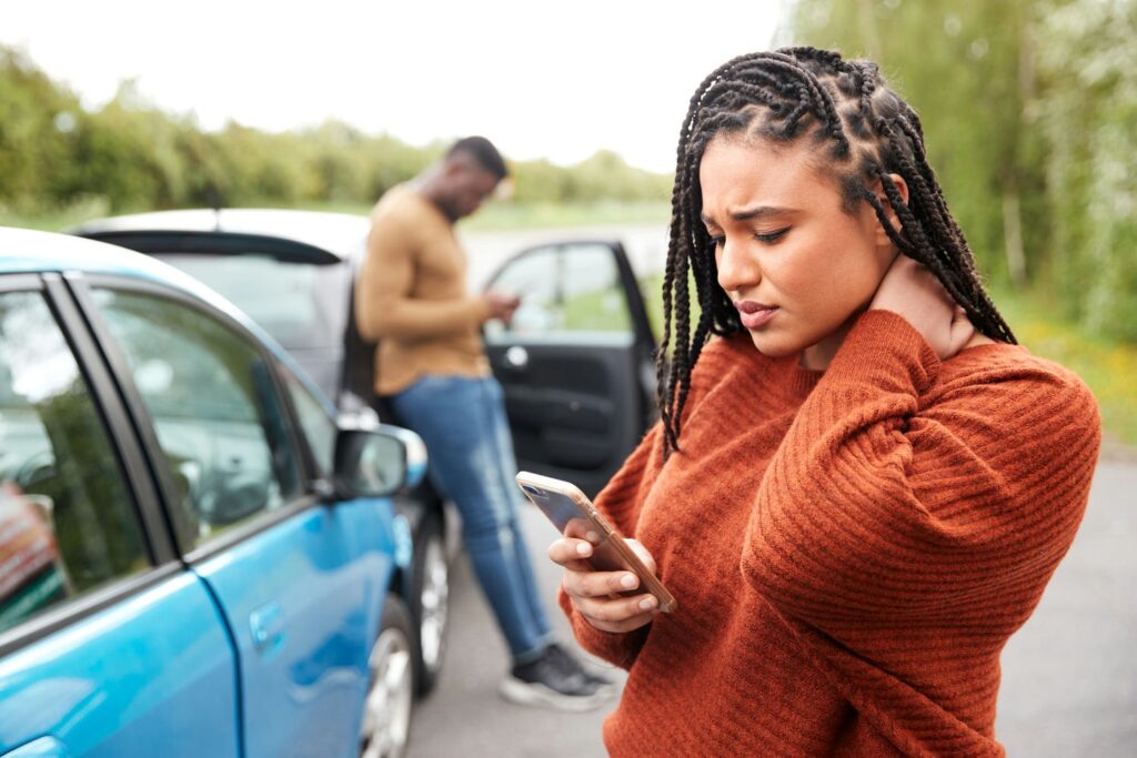 Woman standing beside damaged cars phoning for assistance after an accident.