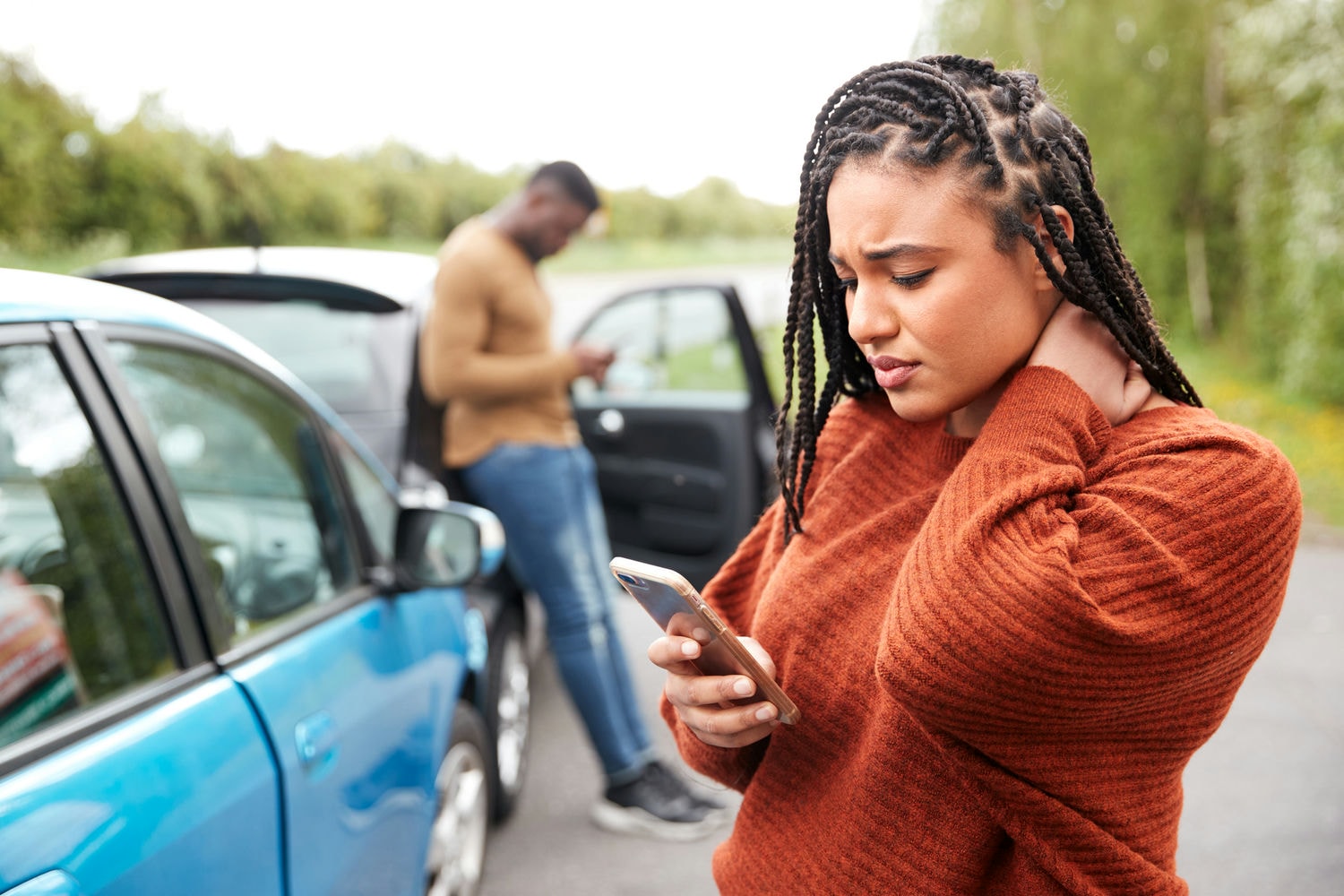 Woman standing beside damaged cars phoning for assistance after an accident.