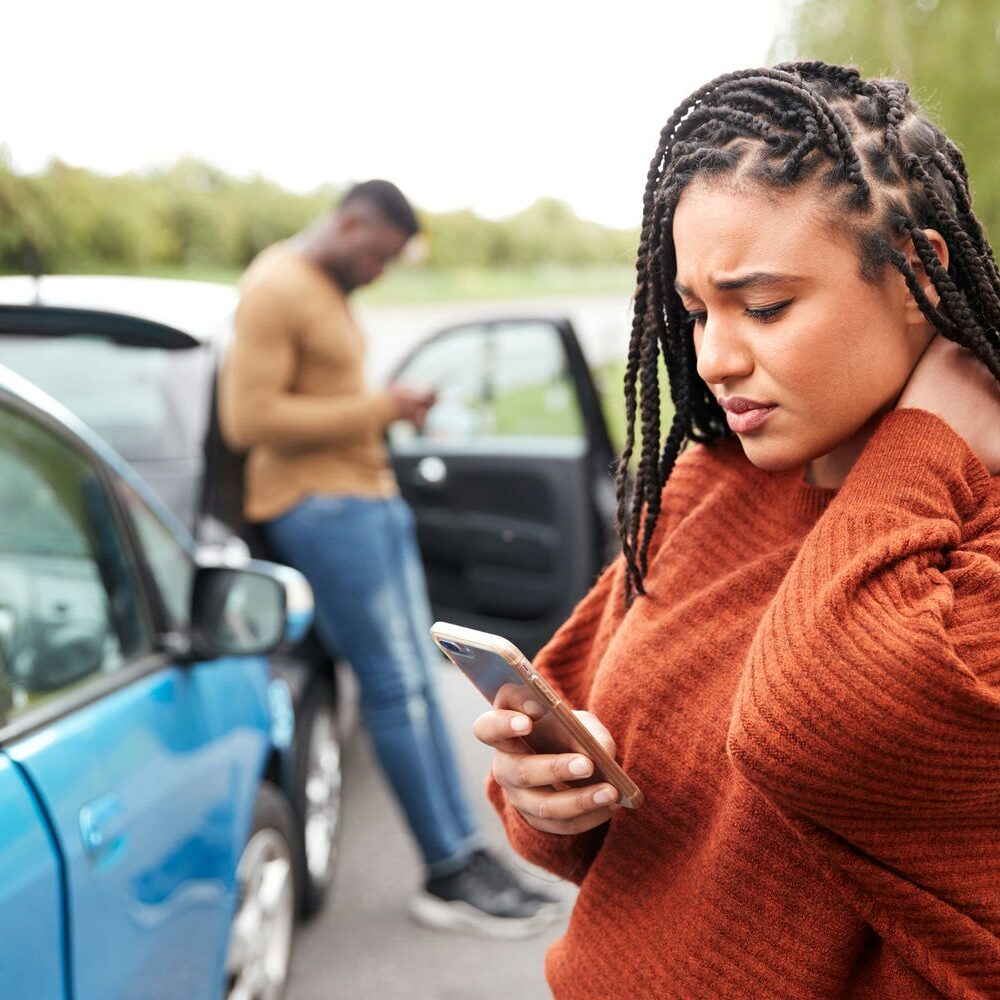 Woman standing beside damaged cars phoning for assistance after an accident.