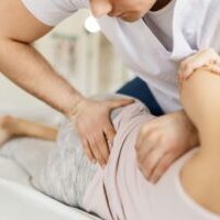 Chiropractor performing shoulder adjustment to relieve muscle tension and pain.