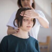 Healthcare professional assessing a patient with post-accident headache and concussion-like symptoms.