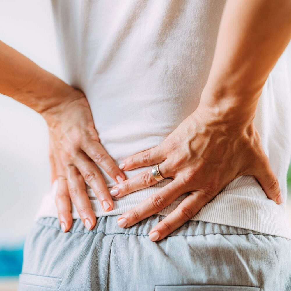 Patient holding the lower back while a clinician supports the torso during pain-relief care.
