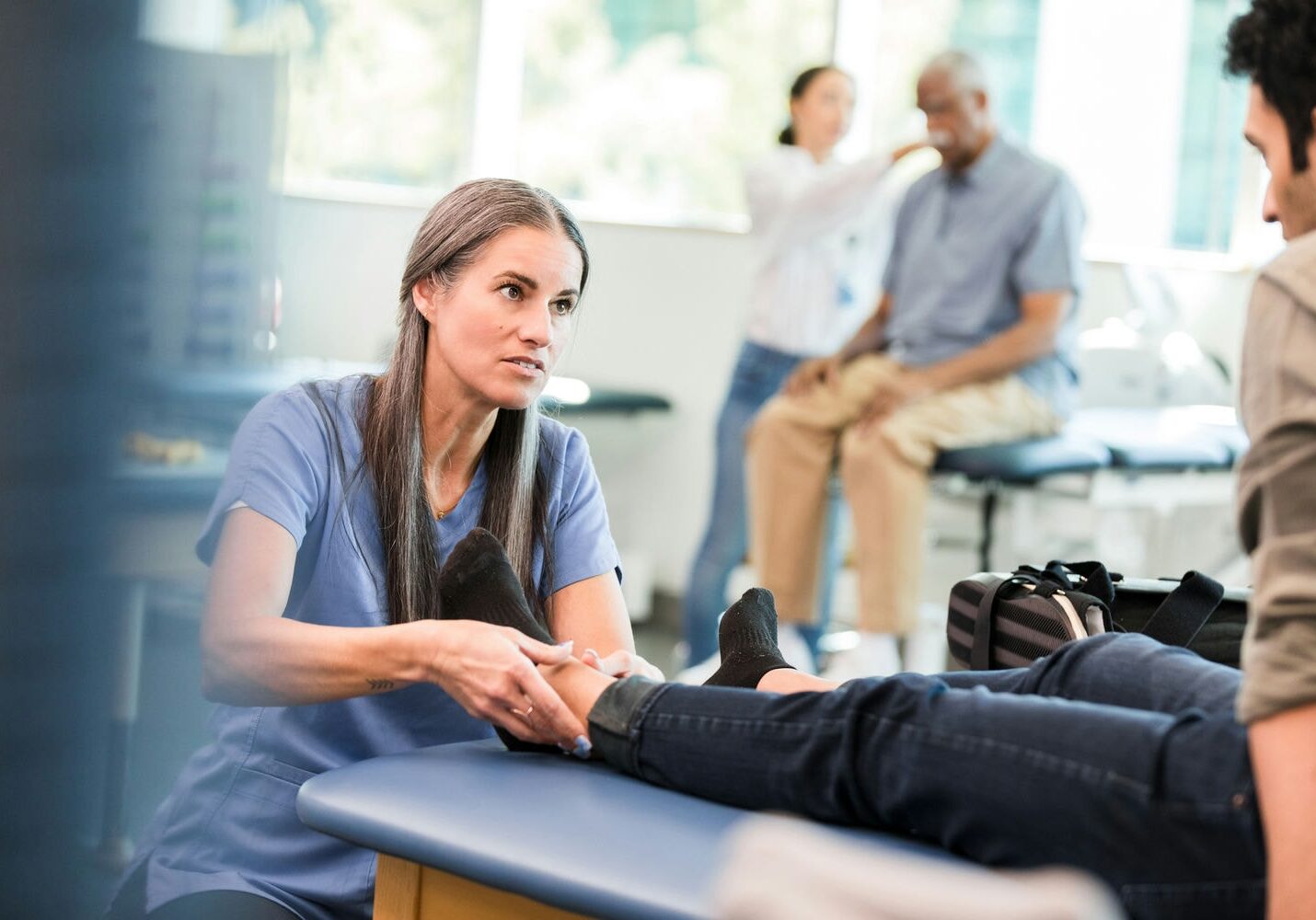 Physio performing hands-on mobilization to a patient’s ankle and foot to restore range of motion.