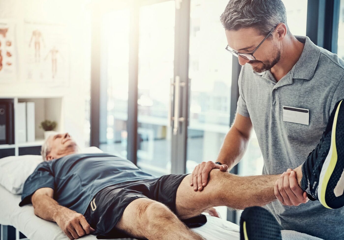 Clinician performing hands-on treatment to a patient’s lower leg and ankle on a treatment table.