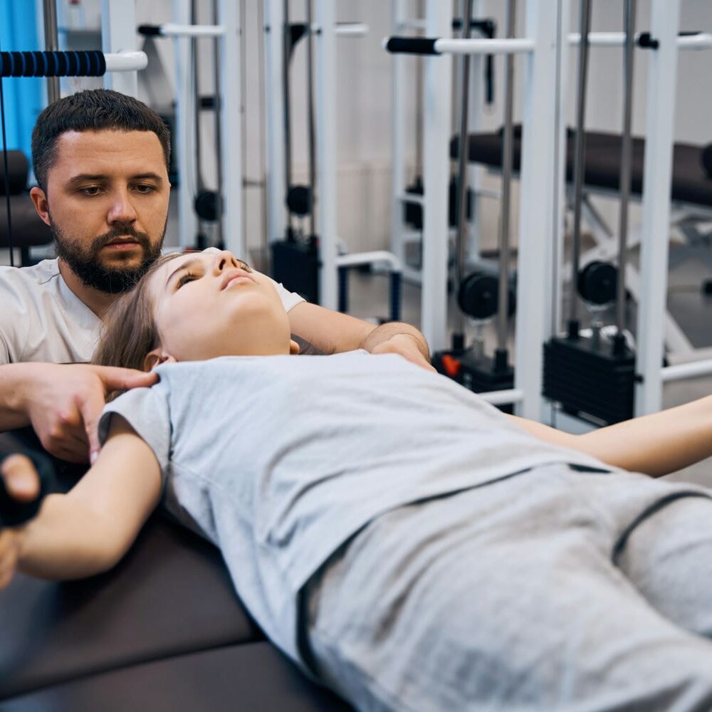 Therapist operating a decompression/traction device while a patient lies strapped on the treatment table.