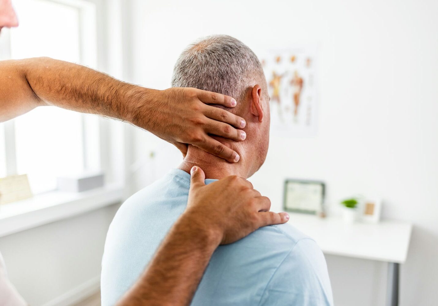 Physiotherapist helping an older man with neck pain through stretching exercises.