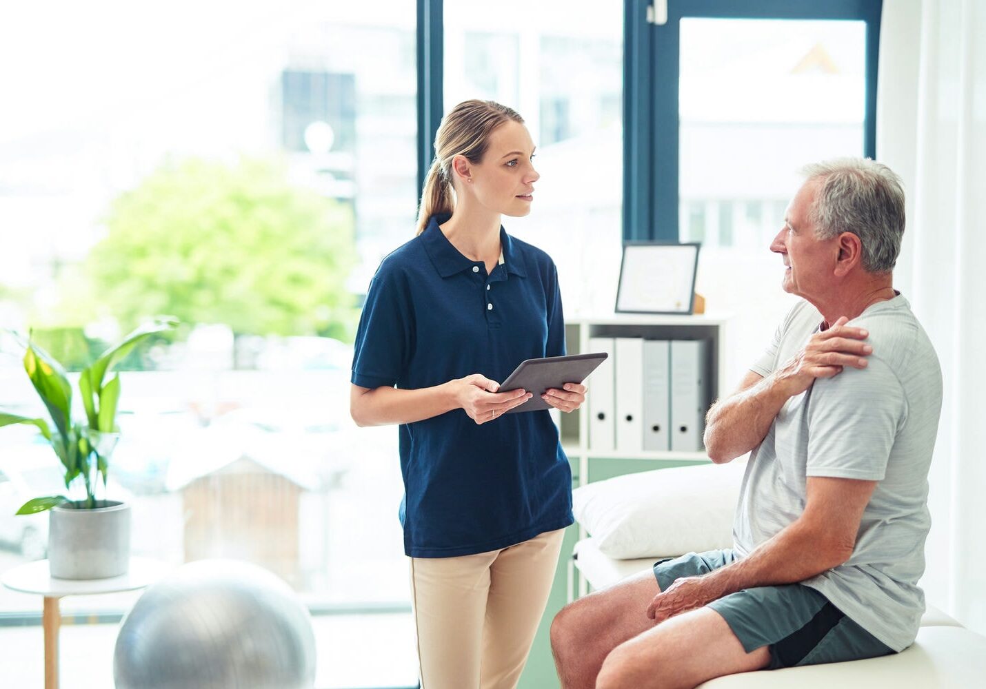 Physiotherapist discussing treatment options with a senior patient in a clinic setting.