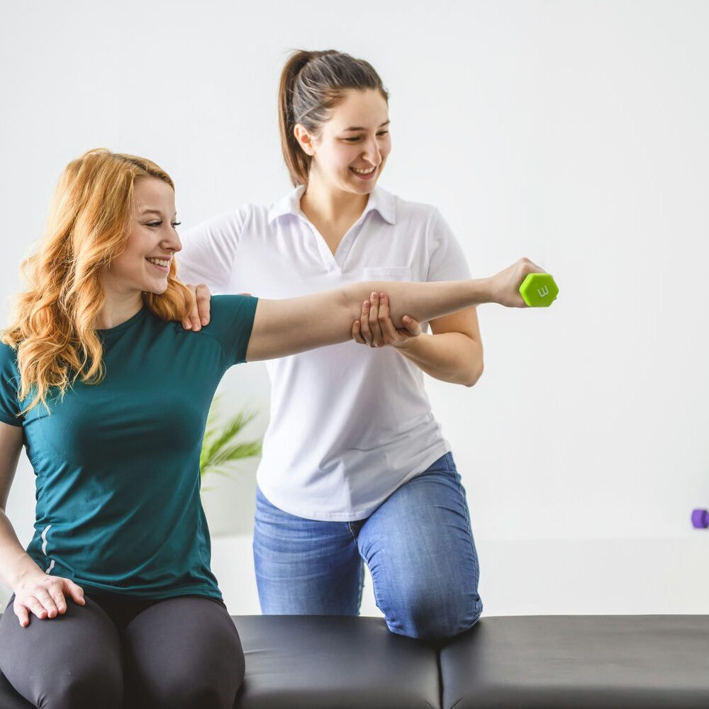 Therapist guiding a patient through light band exercises to build strength and manage chronic pain.
