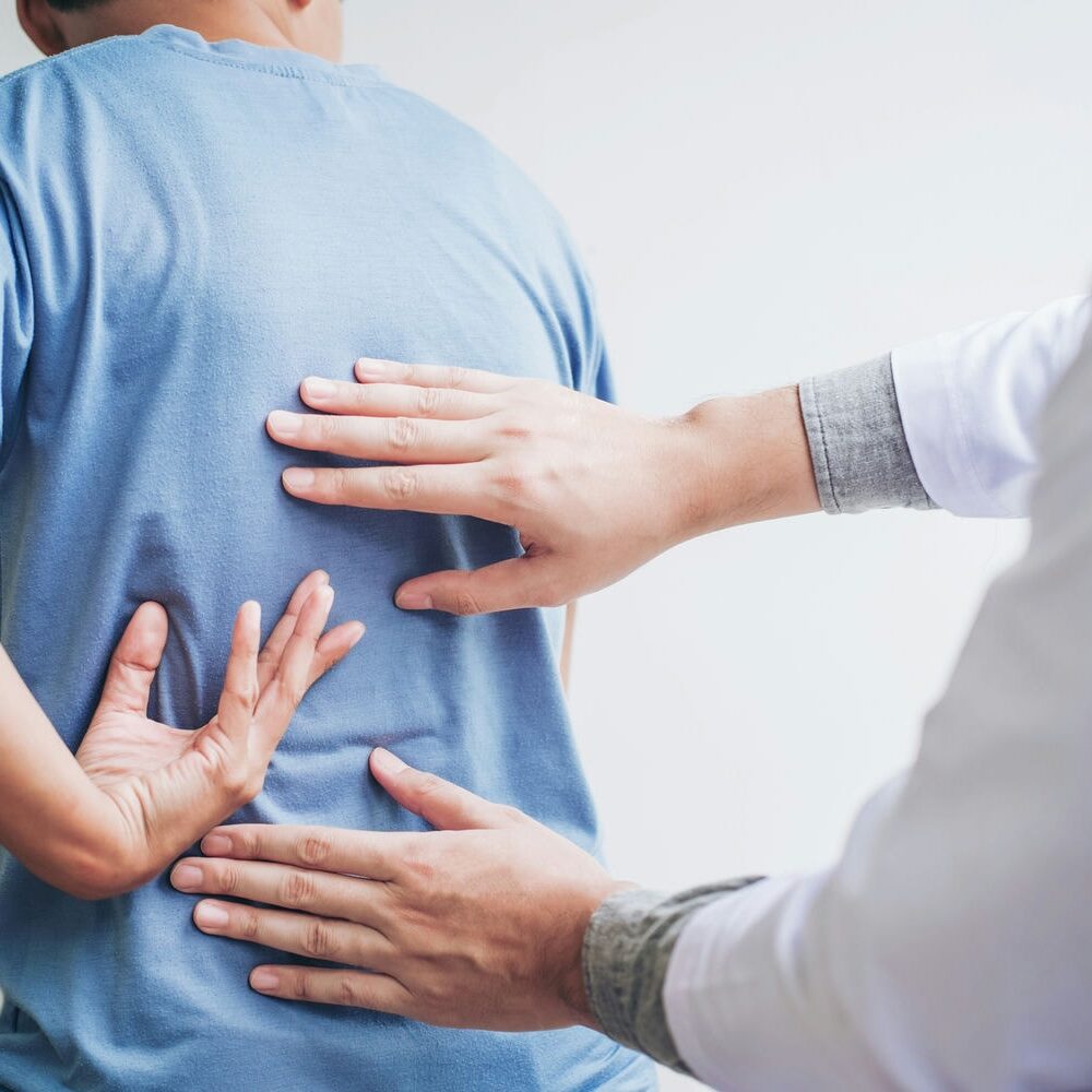 Clinician pointing to shoulder and spine areas while evaluating post-collision pain.