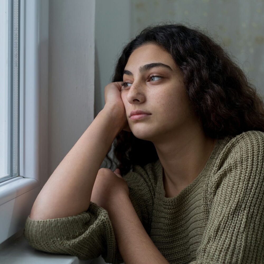 woman looking out the window pondering while suffering with depression
